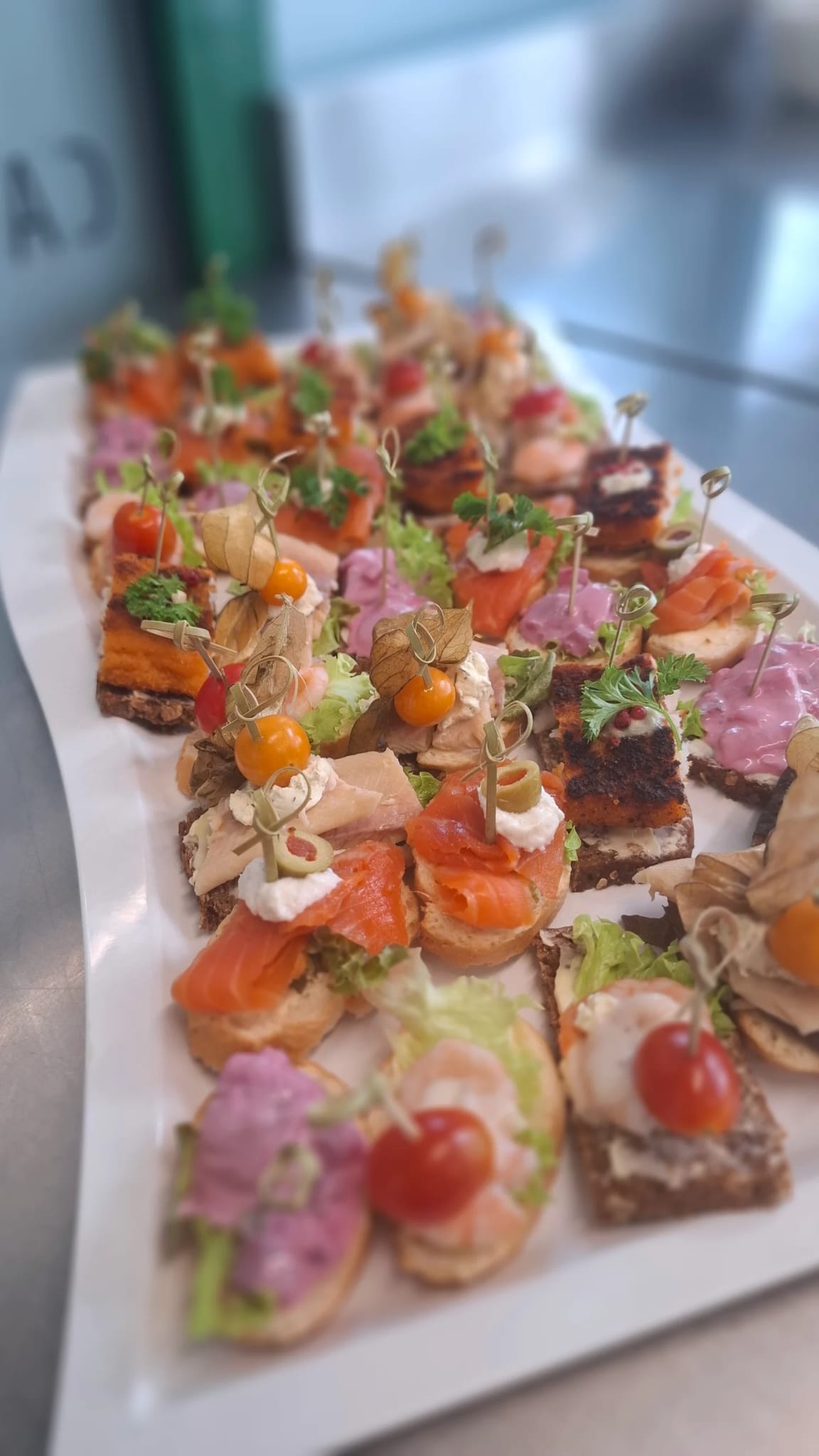 Bunte Canapé-Platte mit Lachs, Garnelen und Frischkäse auf dunklem Brot